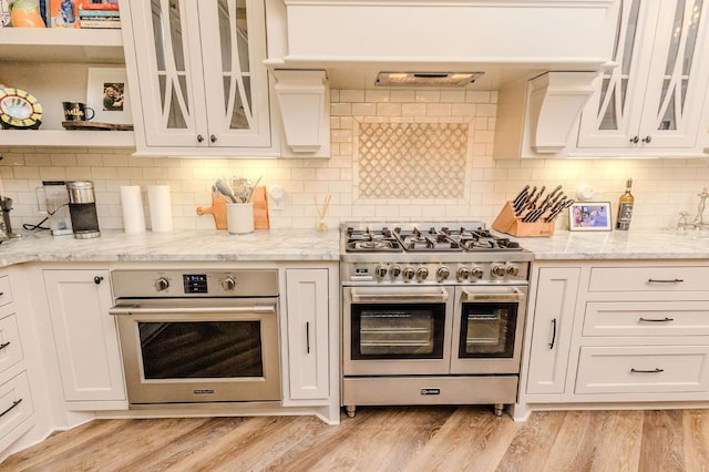 kitchen with light stone counters, light hardwood / wood-style flooring, stainless steel appliances, and white cabinets