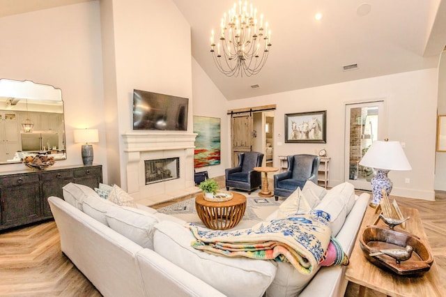 living room with a fireplace, light parquet flooring, a barn door, and high vaulted ceiling