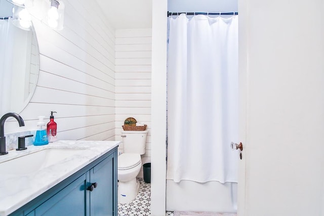 full bathroom with vanity, wood walls, shower / bath combo with shower curtain, and toilet