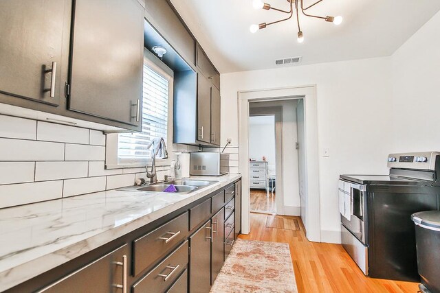 kitchen with sink, light hardwood / wood-style flooring, an inviting chandelier, backsplash, and stainless steel electric range oven