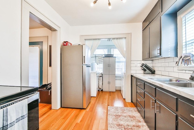 kitchen featuring plenty of natural light, sink, stainless steel refrigerator, and light wood-type flooring