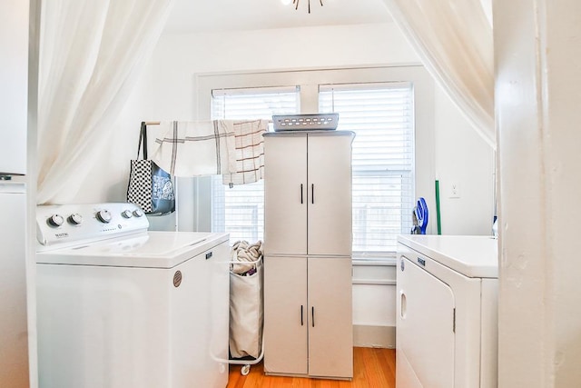 clothes washing area featuring light hardwood / wood-style floors and washing machine and dryer