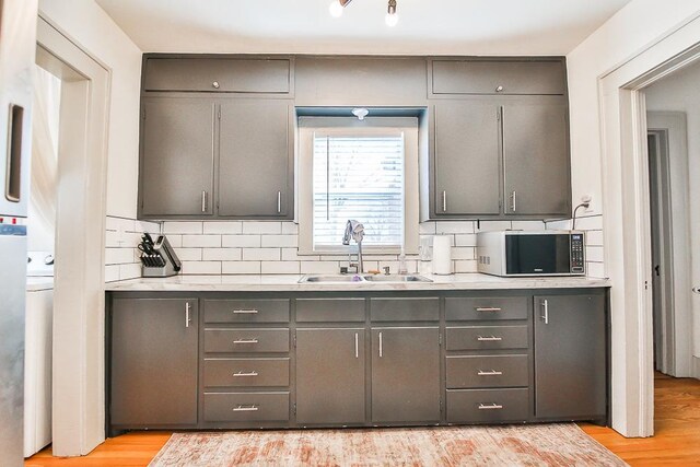 kitchen featuring sink, gray cabinetry, light hardwood / wood-style floors, and decorative backsplash