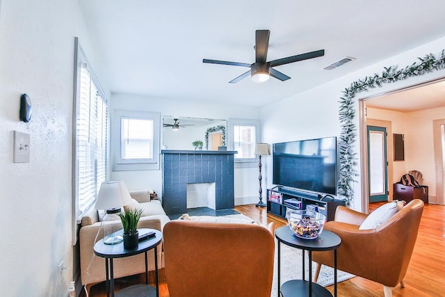 living room featuring ceiling fan, a fireplace, and light hardwood / wood-style flooring