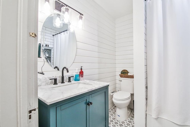 bathroom featuring vanity, wooden walls, and toilet