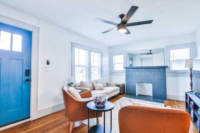 living room with a brick fireplace, hardwood / wood-style flooring, and ceiling fan