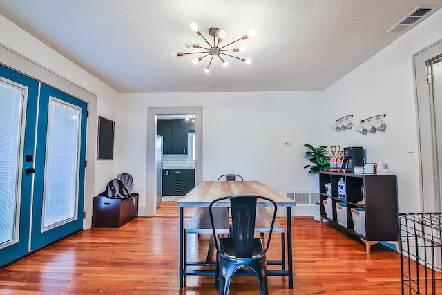 dining room featuring an inviting chandelier, wood-type flooring, and french doors