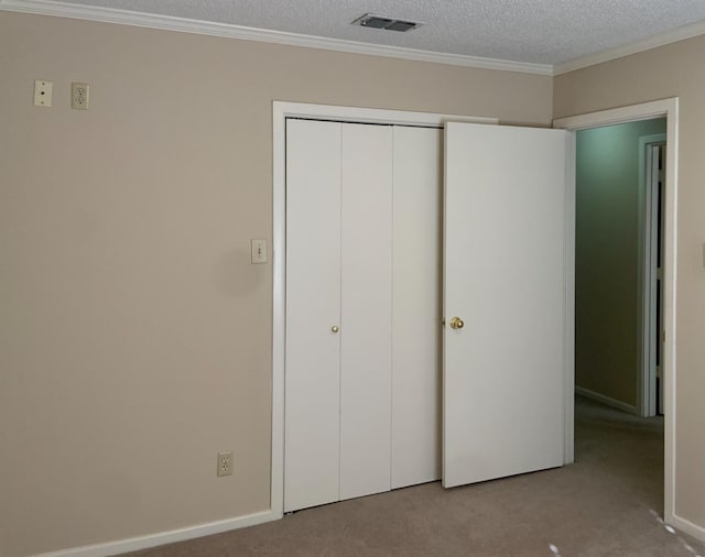 unfurnished bedroom featuring crown molding, light colored carpet, a closet, and a textured ceiling