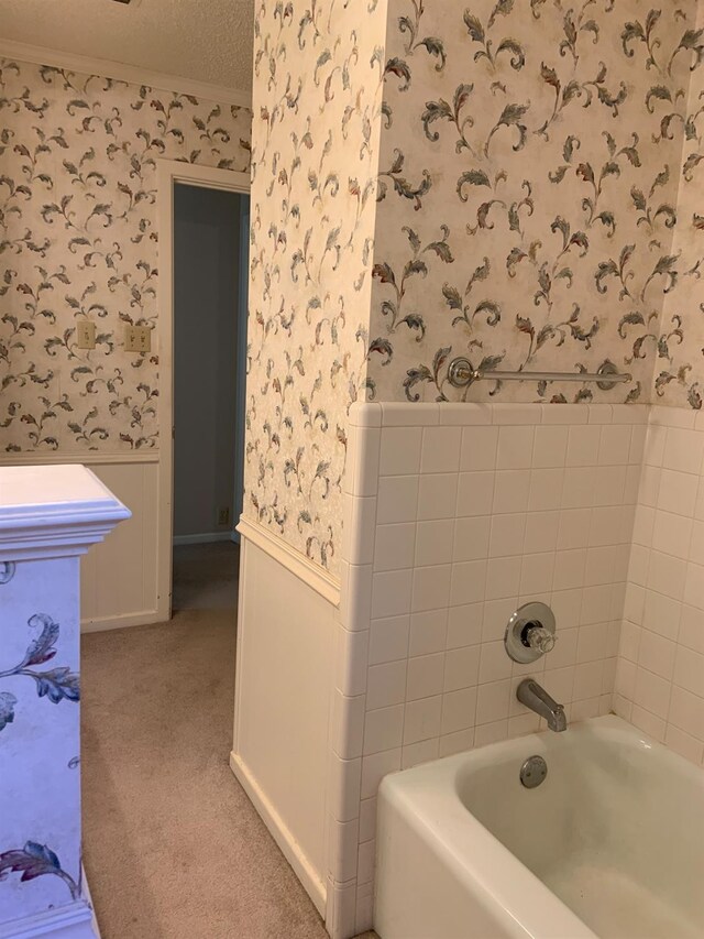 bathroom with ornamental molding, a textured ceiling, and a tub to relax in