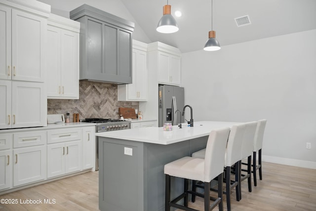 13803 Quinton Ave, Lubbock, TX 79424 - kitchen featuring appliances with stainless steel finishes, decorative backsplash, lofted ceiling, a kitchen breakfast bar, and light countertops