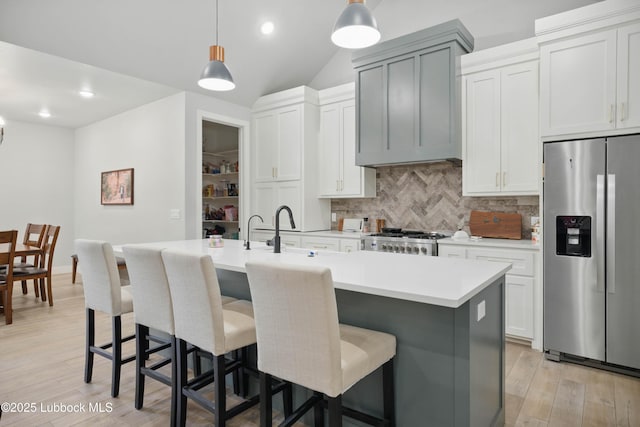 13803 Quinton Ave, Lubbock, TX 79424 - kitchen featuring stainless steel fridge with ice dispenser, tasteful backsplash, light countertops, pendant lighting, and a center island with sink