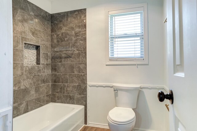 bathroom featuring toilet and tiled shower / bath combo