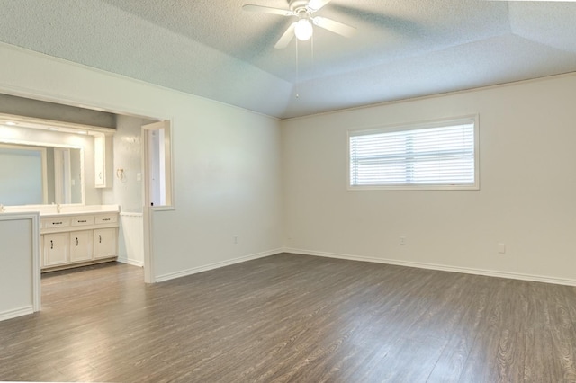 spare room featuring ceiling fan, dark hardwood / wood-style flooring, vaulted ceiling, and a textured ceiling