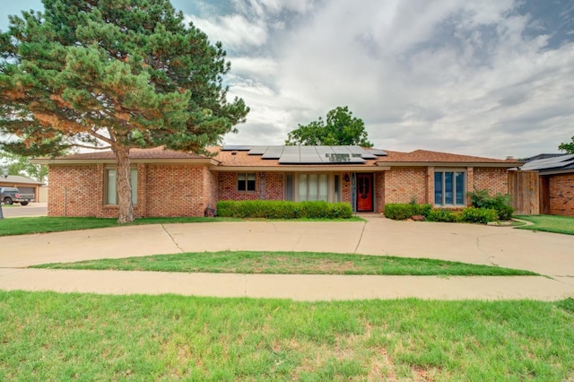 ranch-style home with a front lawn and solar panels