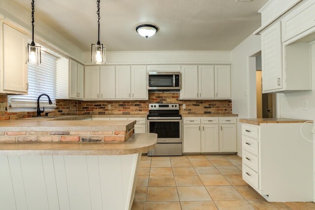 kitchen featuring sink, decorative light fixtures, light tile patterned floors, stainless steel appliances, and white cabinets