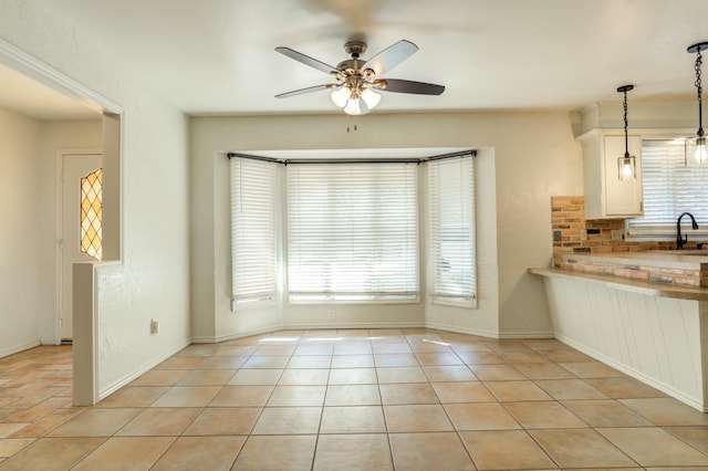 unfurnished dining area with sink, plenty of natural light, ceiling fan, and light tile patterned flooring