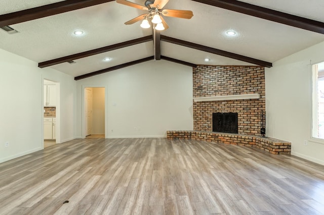 unfurnished living room featuring light hardwood / wood-style floors, a textured ceiling, a brick fireplace, and vaulted ceiling with beams