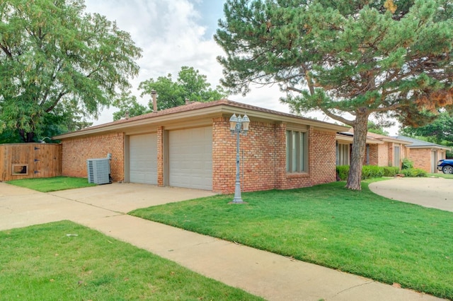 view of front facade with a garage, a front yard, and central air condition unit