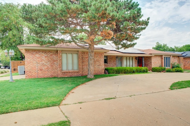 ranch-style home with a front yard and solar panels