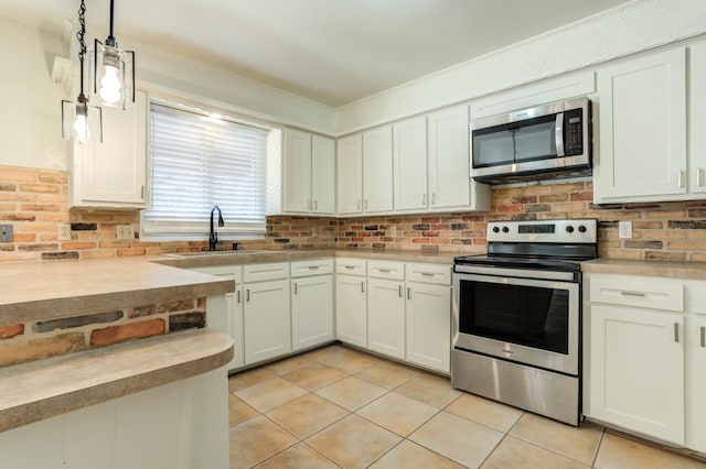 kitchen featuring appliances with stainless steel finishes, sink, pendant lighting, and white cabinets