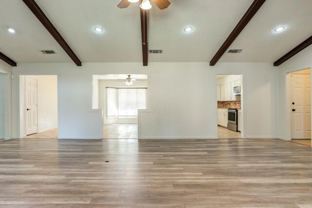 unfurnished living room featuring a textured ceiling, light hardwood / wood-style floors, and beamed ceiling