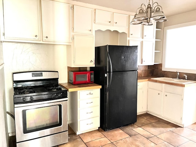 kitchen with sink, black refrigerator, a notable chandelier, decorative light fixtures, and stainless steel range with gas cooktop