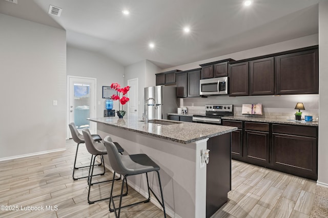 6827 38th St, Lubbock, TX 79407 - kitchen with stainless steel appliances, a sink, a center island with sink, a kitchen bar, and vaulted ceiling