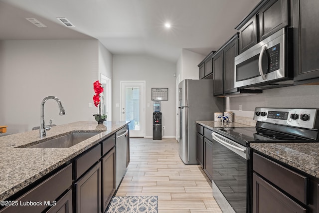 6827 38th St, Lubbock, TX 79407 - kitchen with appliances with stainless steel finishes, a sink, lofted ceiling, light stone counters, and light wood-type flooring