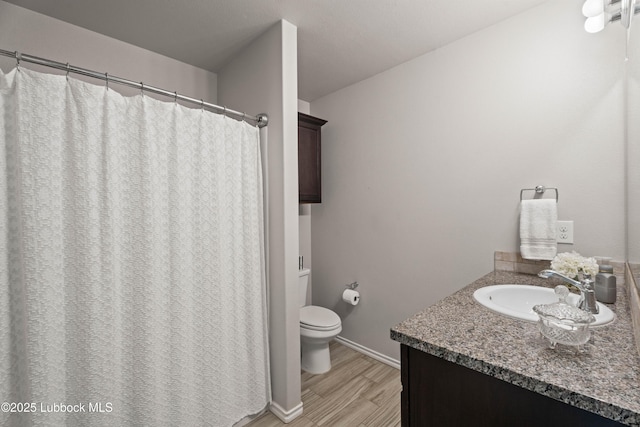 6827 38th St, Lubbock, TX 79407 - bathroom featuring vanity, toilet, wood finished floors, baseboards, and a shower with shower curtain