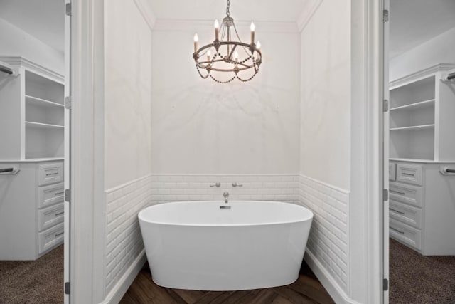 bathroom featuring an inviting chandelier, ornamental molding, and a bathtub