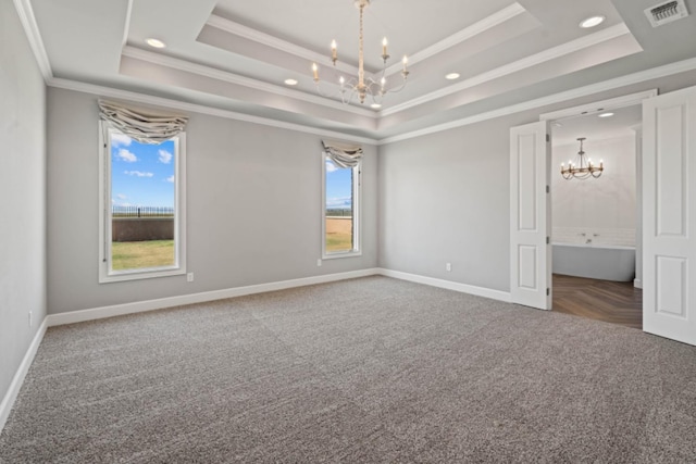 empty room with ornamental molding, a tray ceiling, a chandelier, and carpet