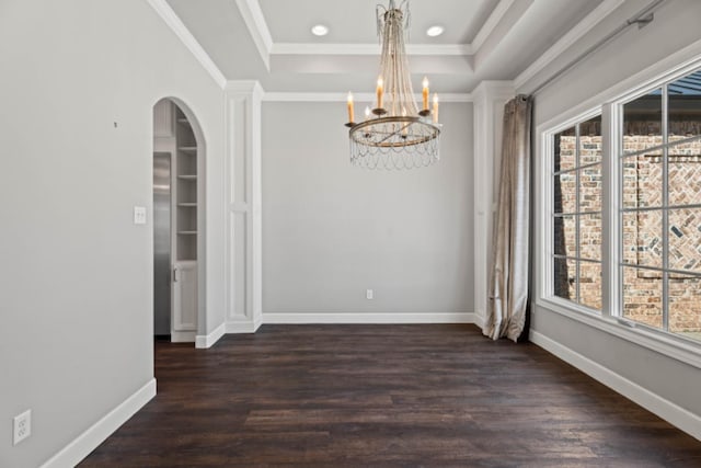 spare room with dark hardwood / wood-style floors, ornamental molding, a tray ceiling, and an inviting chandelier