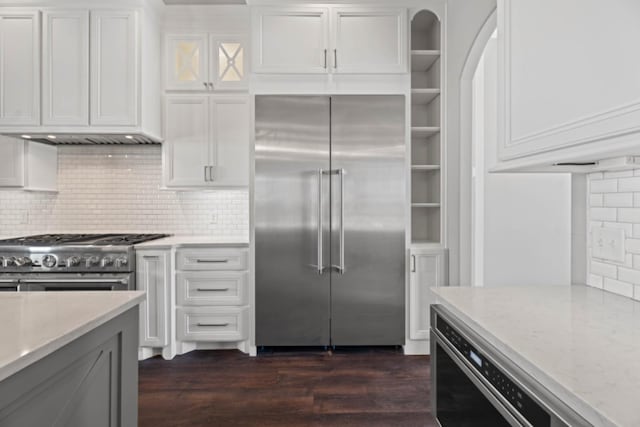 kitchen featuring white cabinets, light stone countertops, exhaust hood, and premium appliances