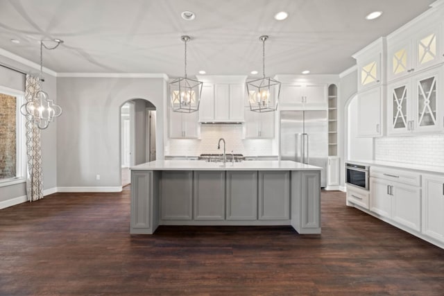 kitchen featuring sink, white cabinetry, hanging light fixtures, a center island with sink, and built in fridge