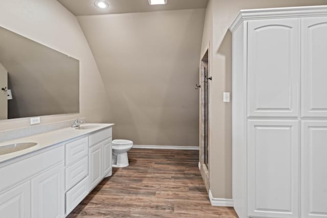 bathroom featuring wood-type flooring, lofted ceiling, vanity, an enclosed shower, and toilet