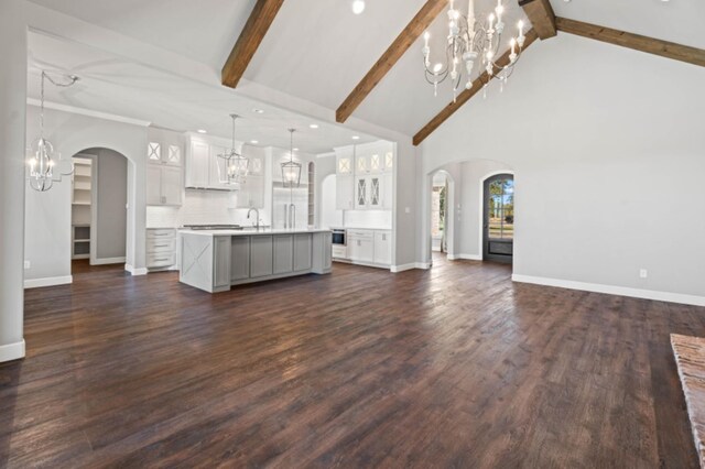 unfurnished living room with dark wood-type flooring, beamed ceiling, sink, and a notable chandelier