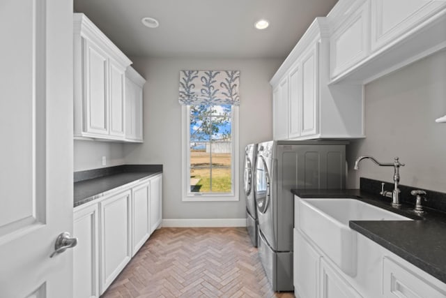 clothes washing area featuring cabinets, washer and clothes dryer, sink, and light parquet floors