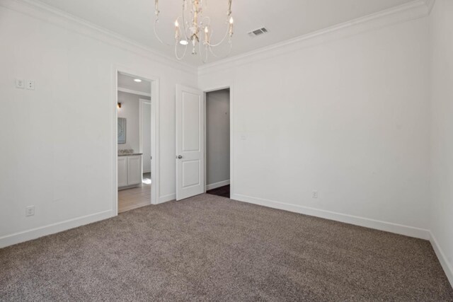 spare room featuring ornamental molding, carpet flooring, and a chandelier