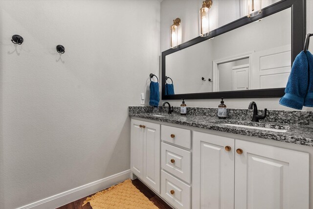 5604 117th St, Lubbock, TX 79424 - bathroom featuring baseboards, double vanity, and wood finished floors