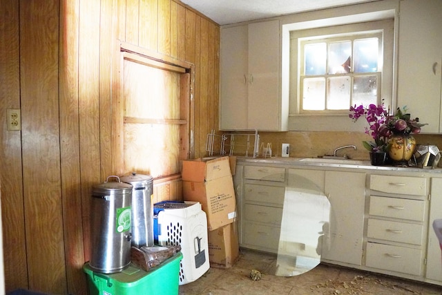 2007 25th St, Lubbock, TX 79411 - kitchen featuring light countertops, wooden walls, a sink, and light tile patterned floors