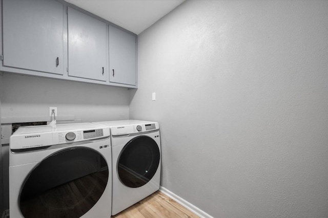 washroom with independent washer and dryer, cabinets, and light hardwood / wood-style floors