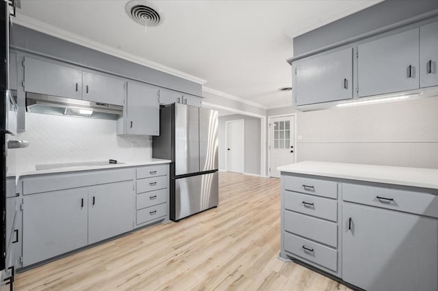 kitchen with ornamental molding, black electric stovetop, stainless steel fridge, and light hardwood / wood-style flooring