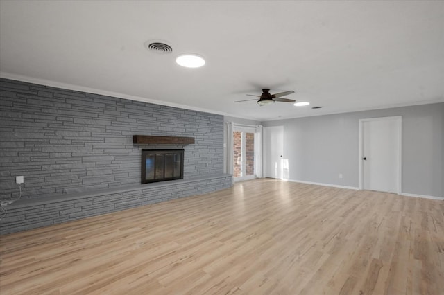 unfurnished living room featuring ceiling fan, a stone fireplace, ornamental molding, and light wood-type flooring