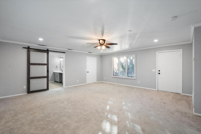 carpeted spare room with ceiling fan, ornamental molding, and a barn door