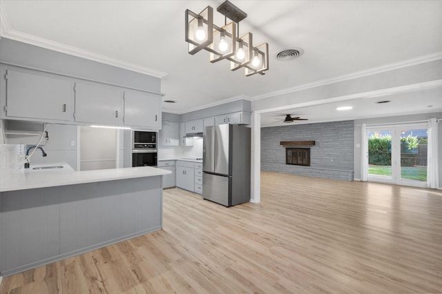 kitchen featuring sink, hanging light fixtures, stainless steel appliances, a brick fireplace, and kitchen peninsula