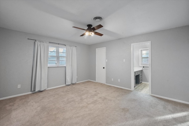 interior space featuring light colored carpet, ceiling fan, and ensuite bathroom