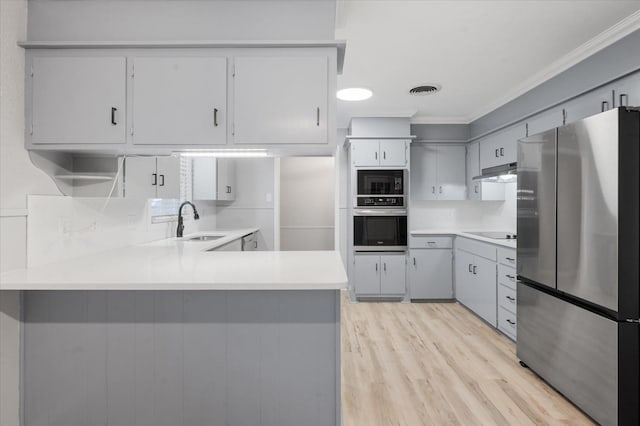 kitchen with sink, light hardwood / wood-style flooring, ornamental molding, kitchen peninsula, and black appliances