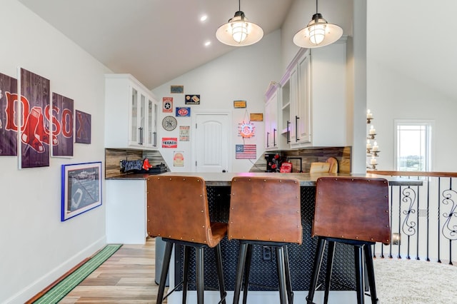 kitchen with tasteful backsplash, white cabinetry, a kitchen breakfast bar, and kitchen peninsula