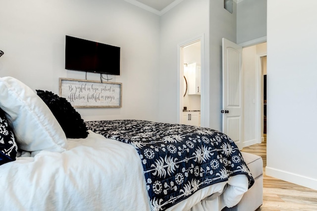 bedroom featuring ornamental molding, ensuite bathroom, and hardwood / wood-style floors