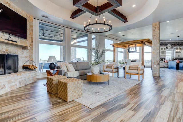 living room with an inviting chandelier, a fireplace, beam ceiling, and hardwood / wood-style flooring